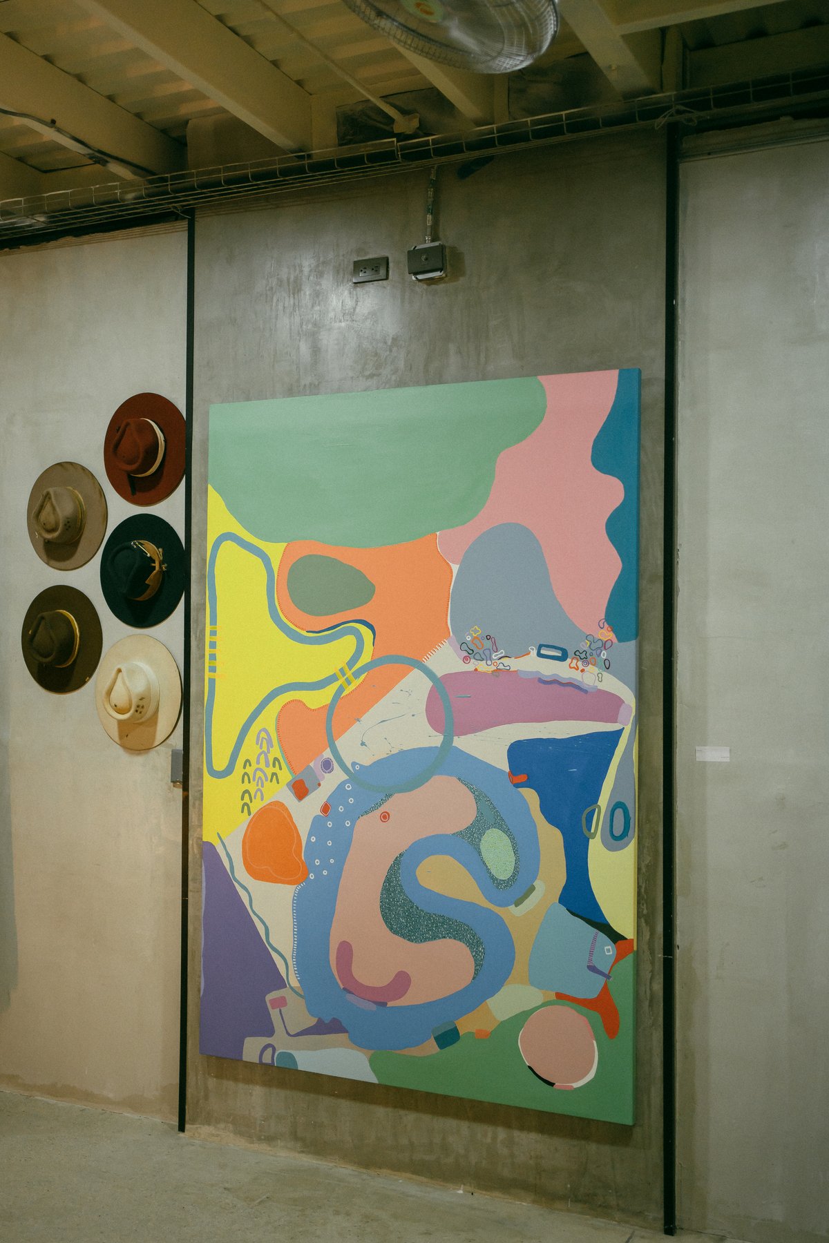 Hats and abstract painting on concrete wall